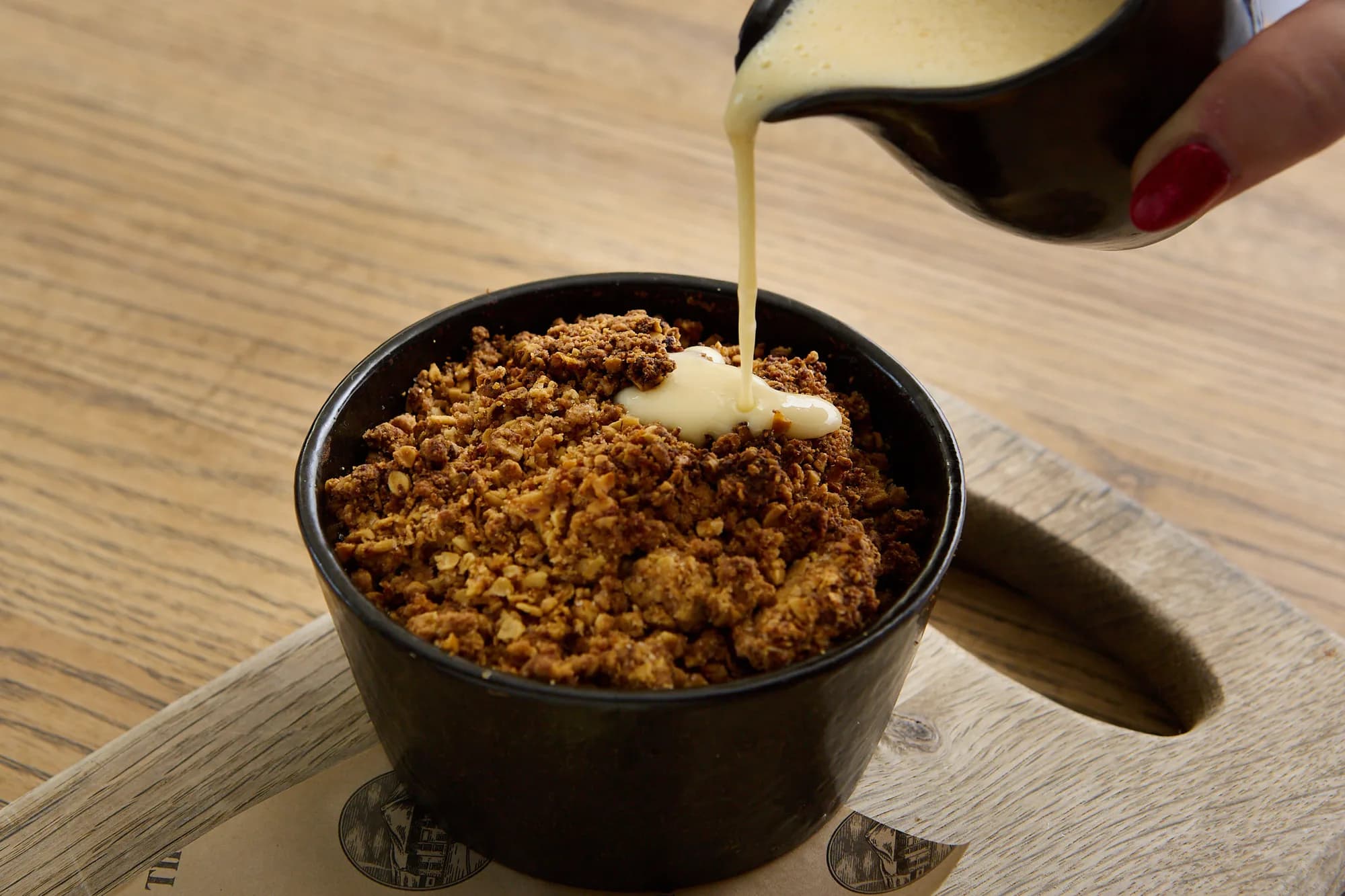 Custard being poured over a crumble at The Old Dog