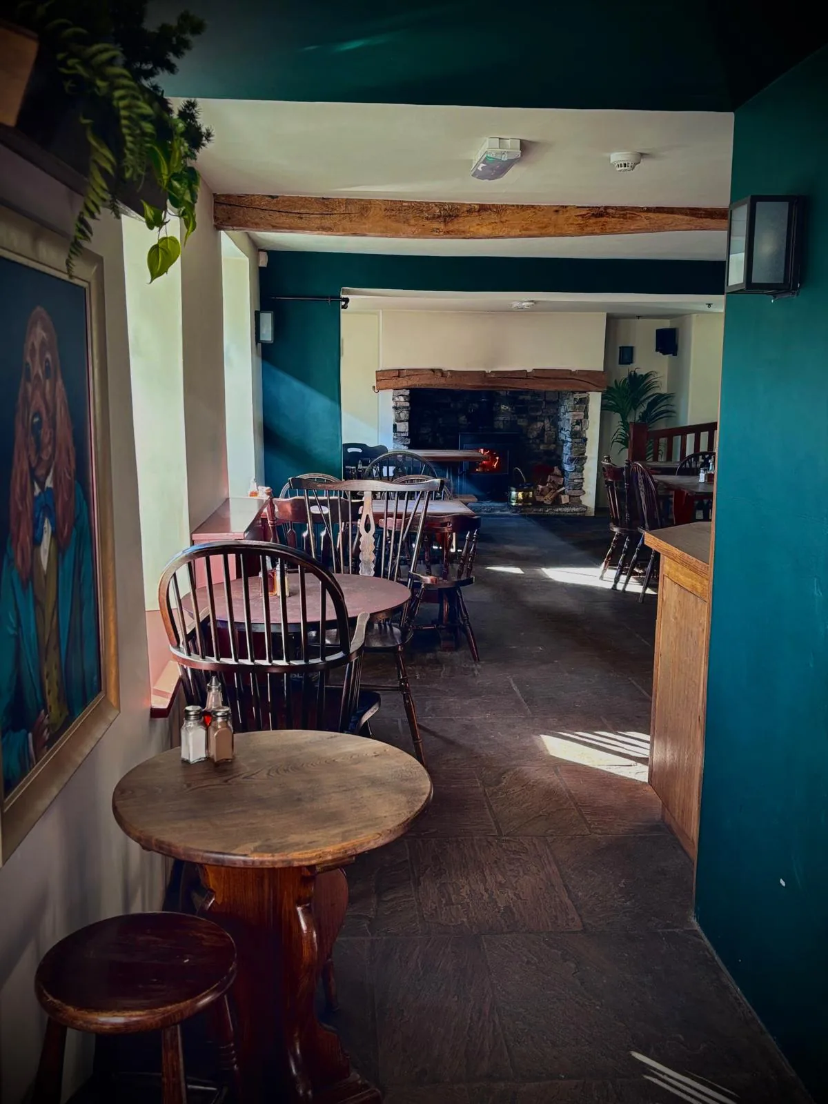 Tables and chairs in The Old Dog, with a lit fireplace at the back